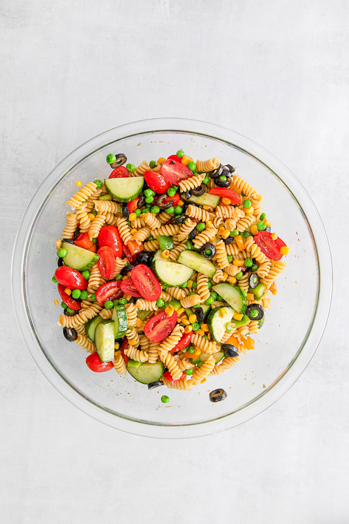 Pasta salad tossed with dressing in a bowl. 