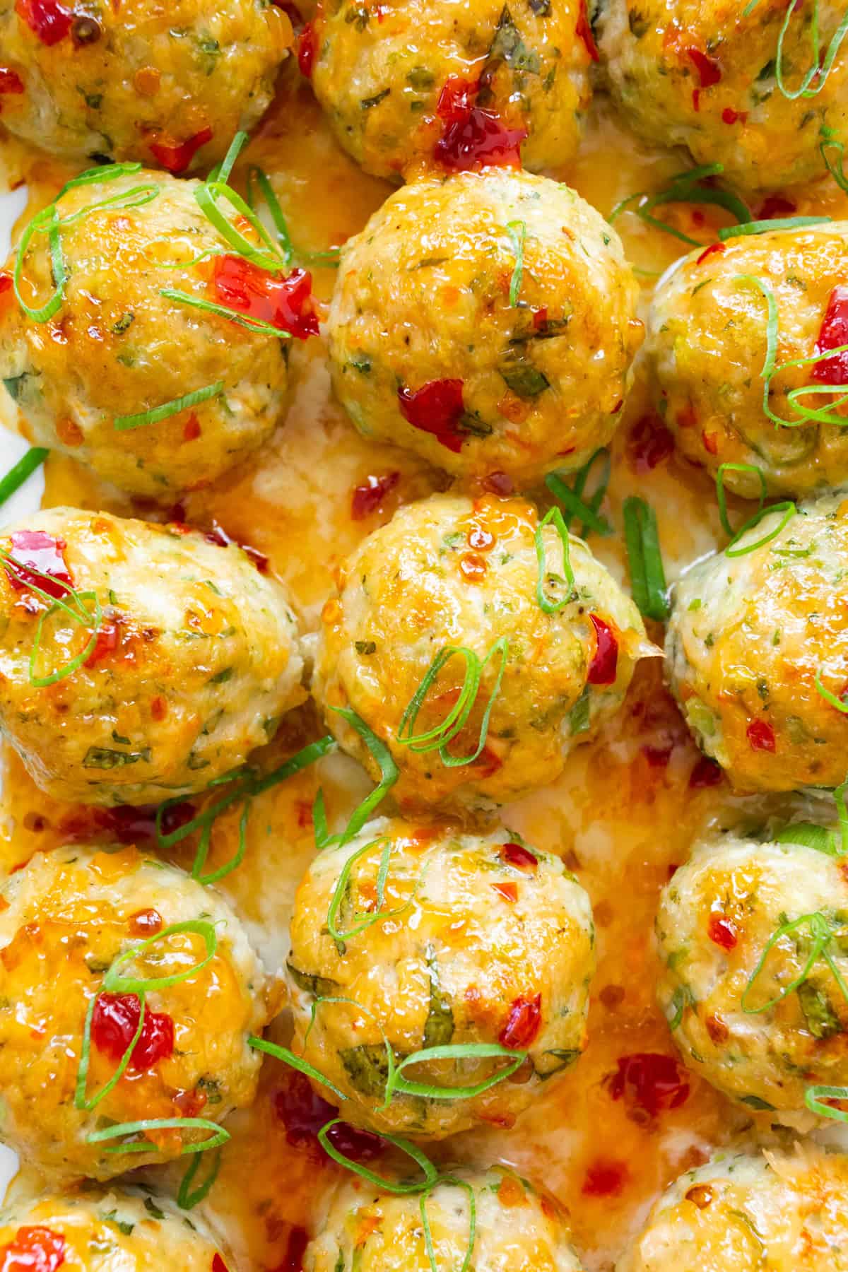 Easy Thai Baked Chicken Meatballs topped with sweet chili sauce and green onions.