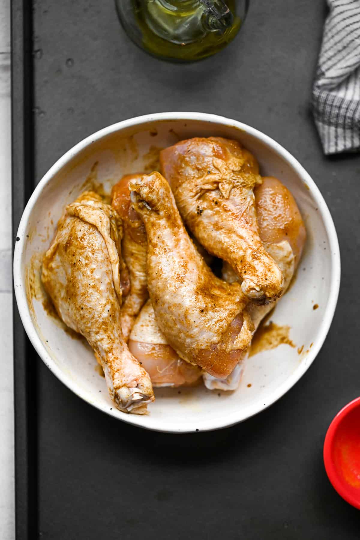 A bowl of raw chicken seasoned in a bowl. 