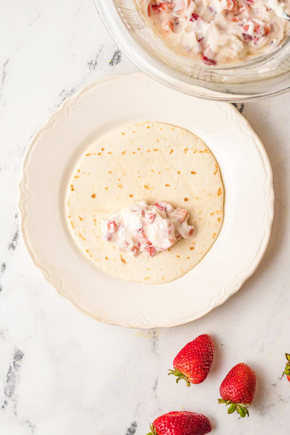 A tortilla with strawberry cheesecake filling sitting on it. 