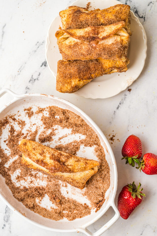 Air Fryer Strawberry Cheesecake Chimichangas being tossed in cinnamon sugar. 