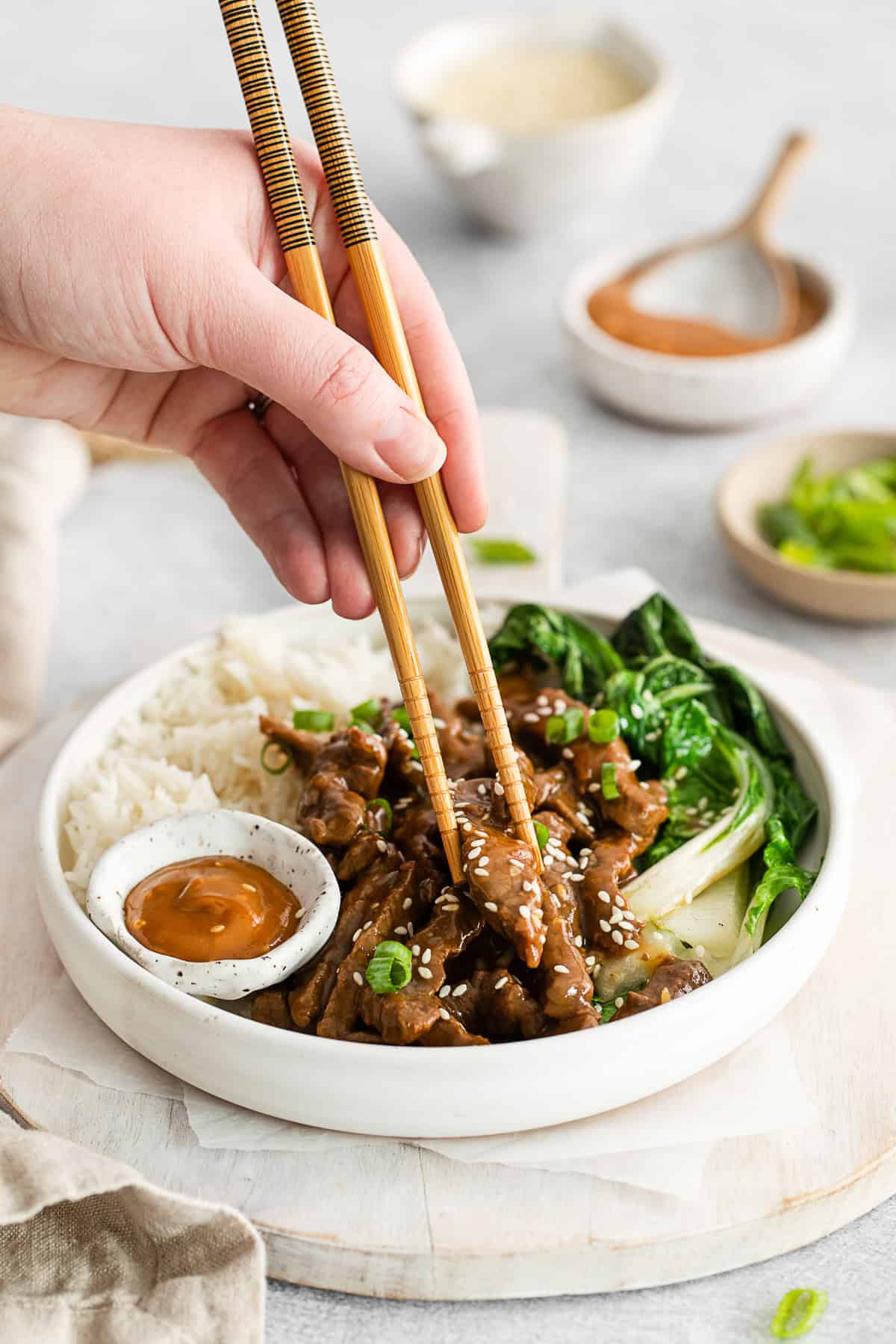 Chopsticks picking up a piece of beef. 