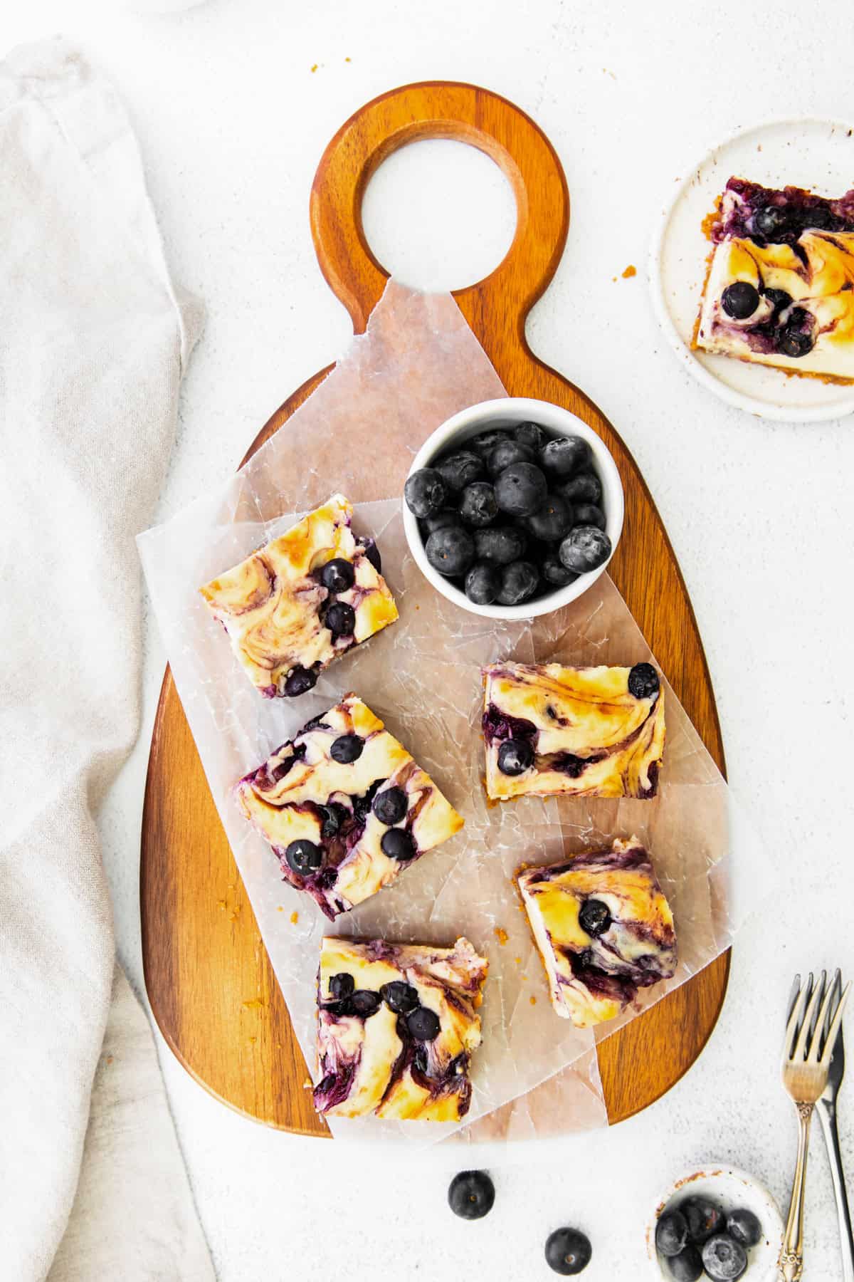 Blueberry Cheesecake Bars on a wooden serving board. 