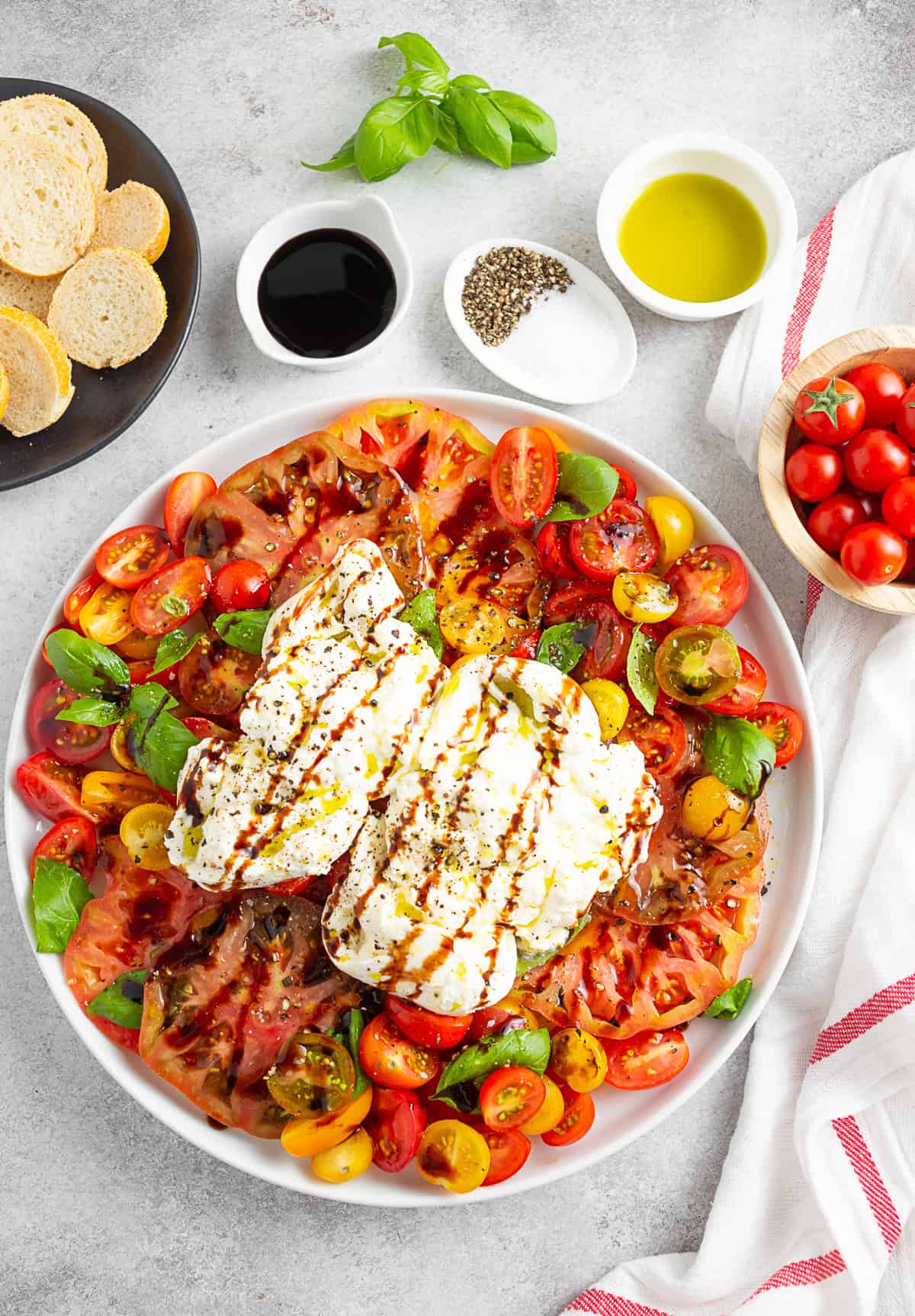 Burrata Caprese Salad on a large white plate with a side of bread. 