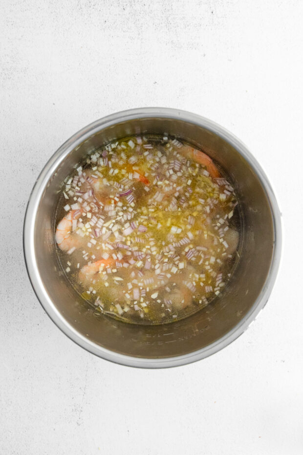 Shrimp and shallots with water in an Instant Pot. 
