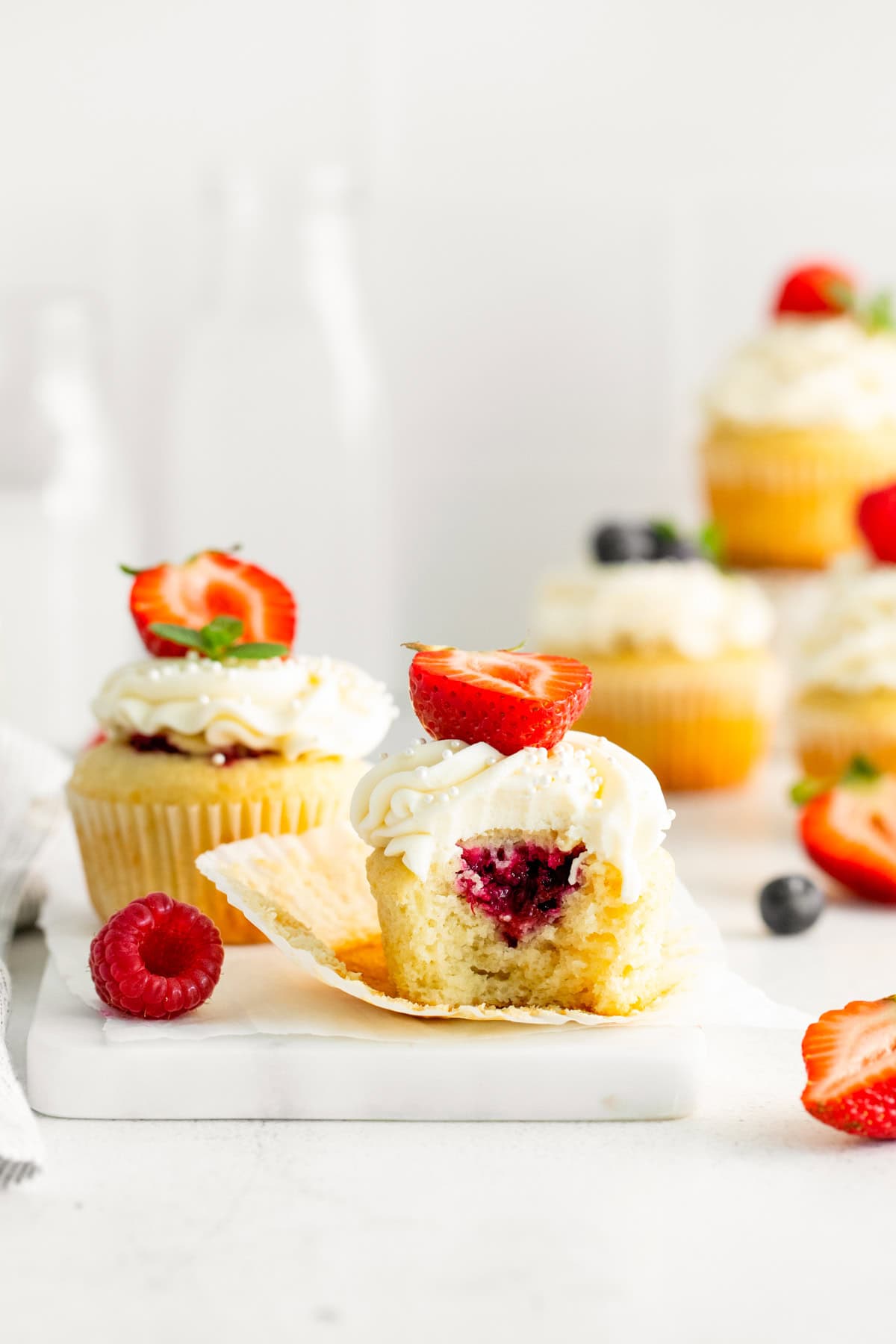 A bite taken out of a Mascarpone Berry Cupcakes to show the berry filling. 