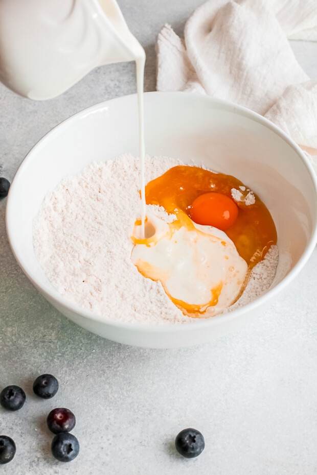 Pouring milk into donut batter.