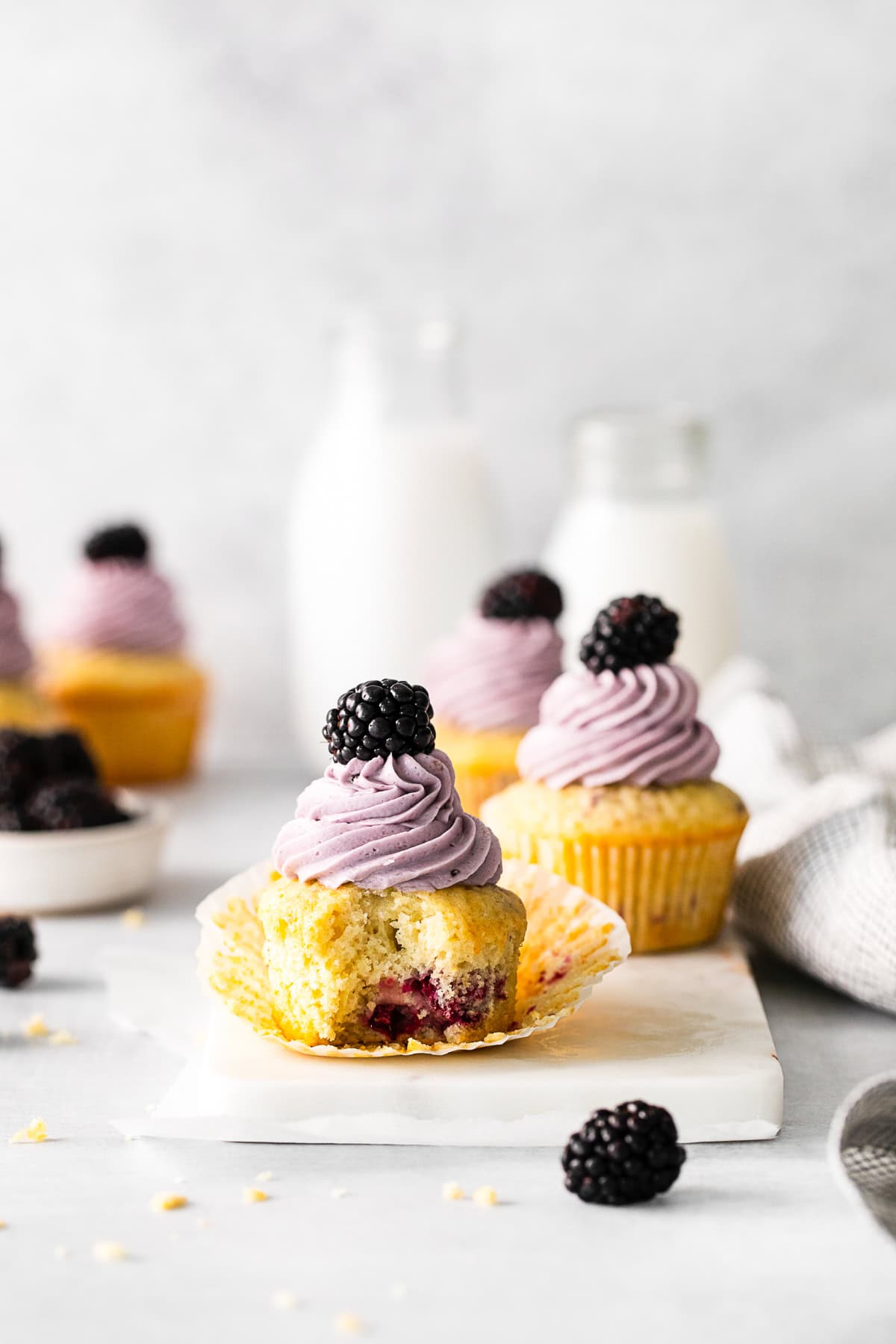 A Blackberry Cupcake with a bite taken out of it.
