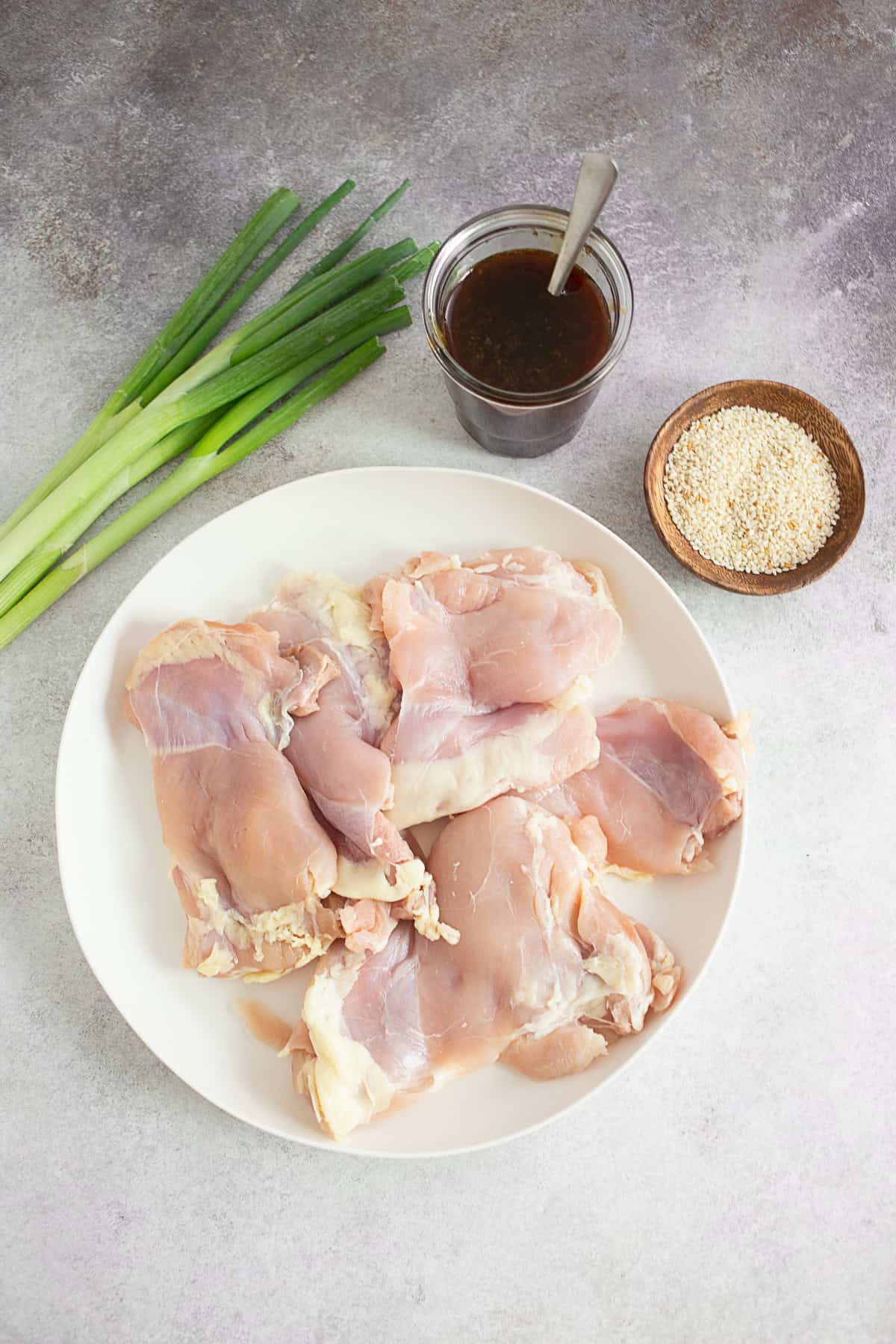 Raw chicken and teriyaki sauce on a table.