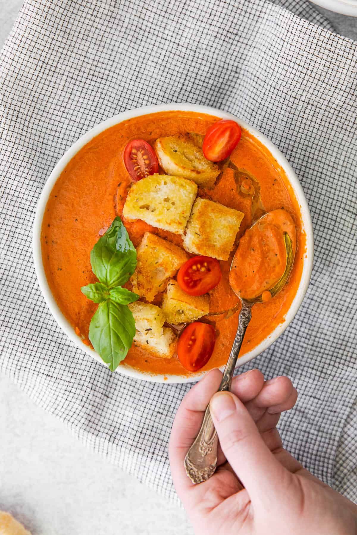 A spoon taking a spoonful of tomato soup.