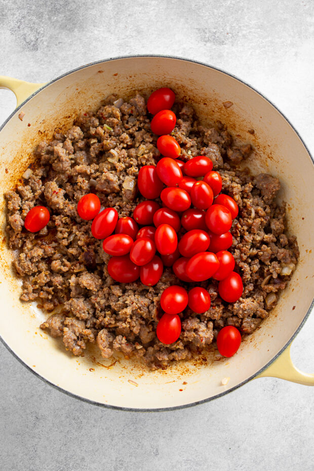Tomatoes in a skillet with Italian sausage. 