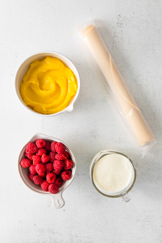 Lemon curd, raspberries and pie crust on a table. 