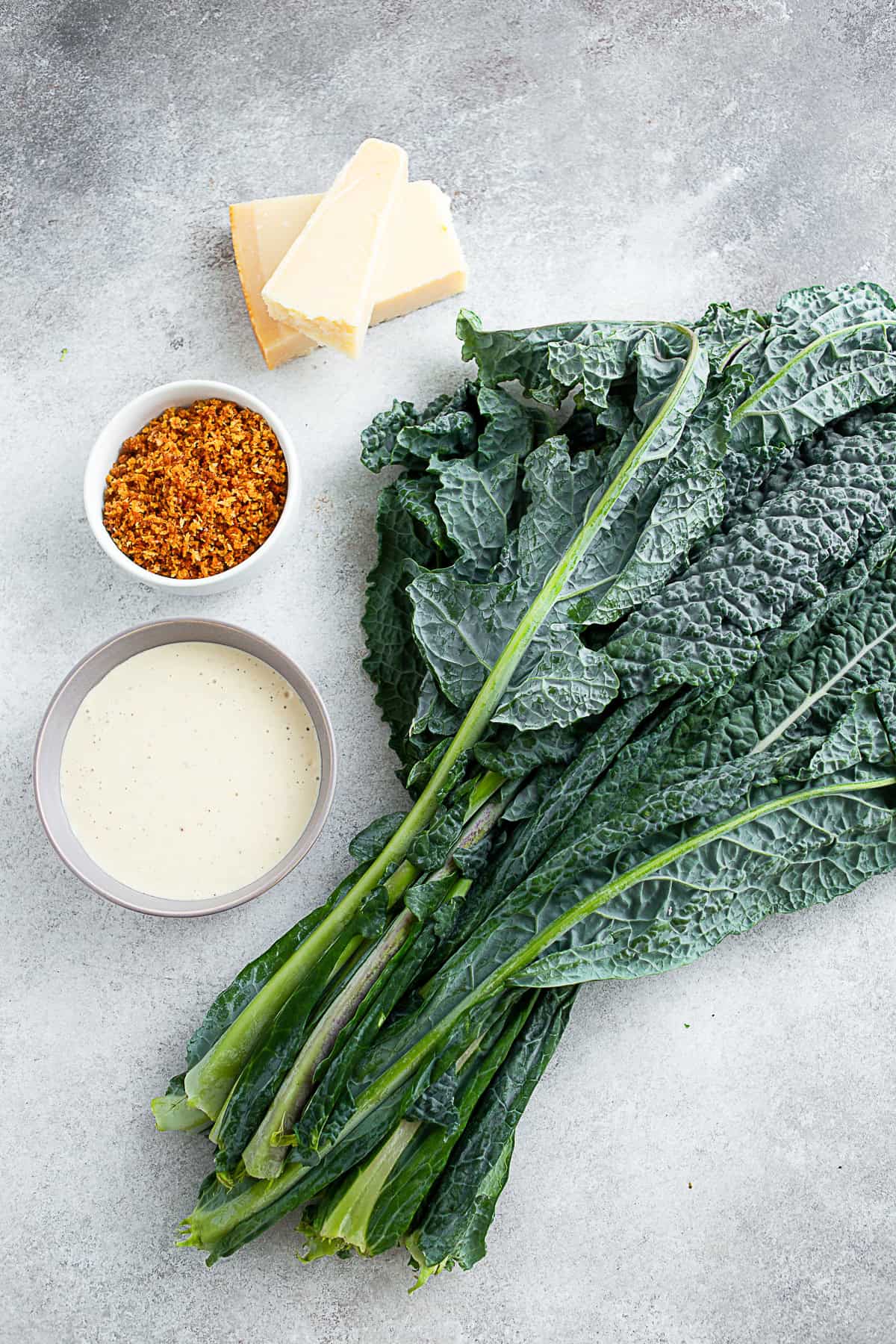 Lacinato kale, Caesar dressing, and toasted panko sitting on a table. 