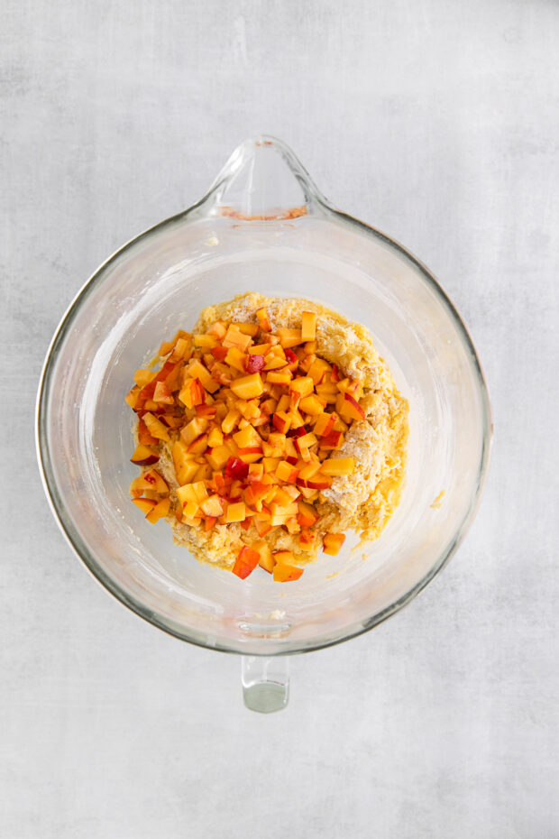 Fresh chopped peaches in a bowl of pound cake batter. 