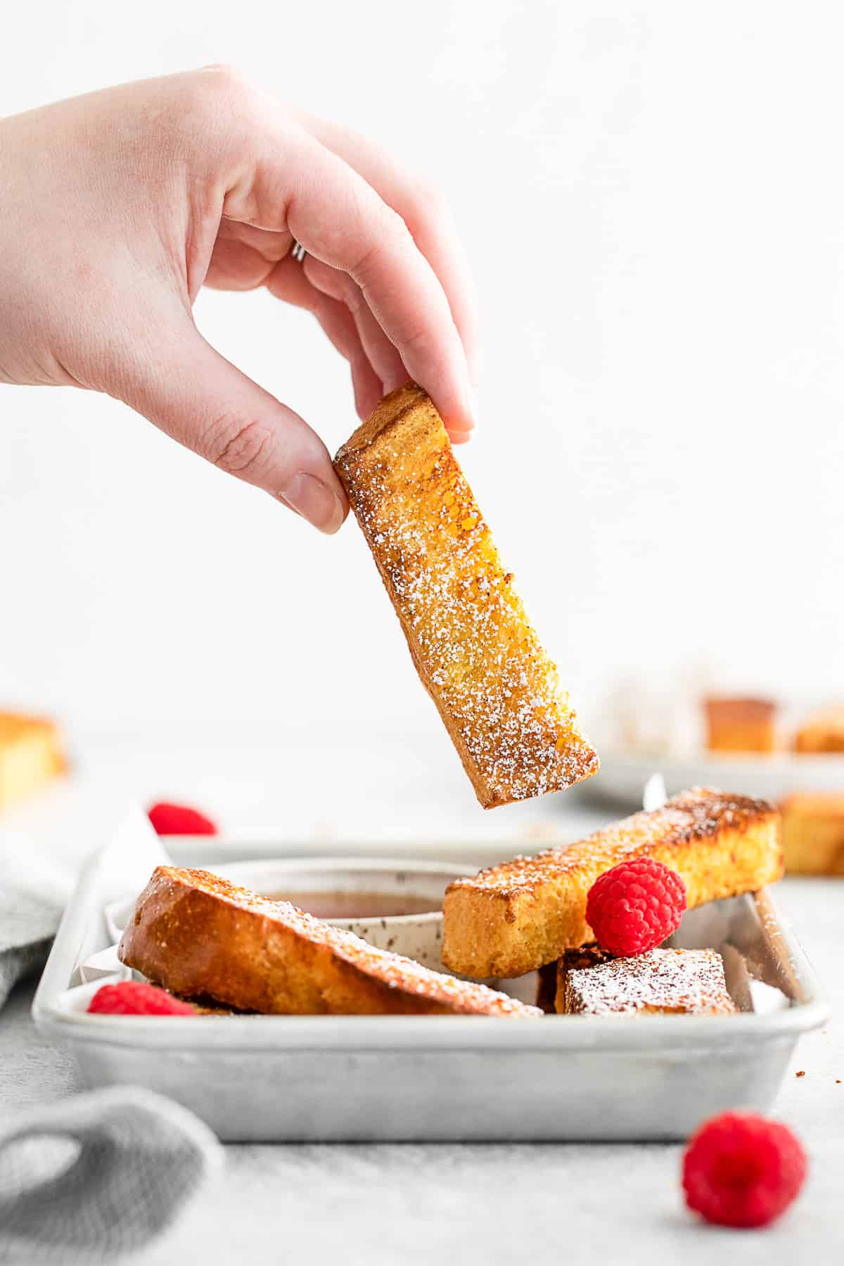 A hand picking up a french toast stick.