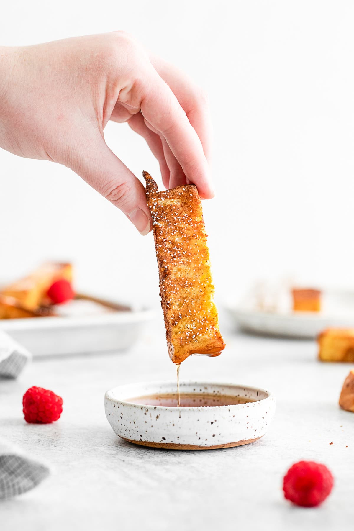 Dipping an Air Fryer French Toast Stick into maple syrup.