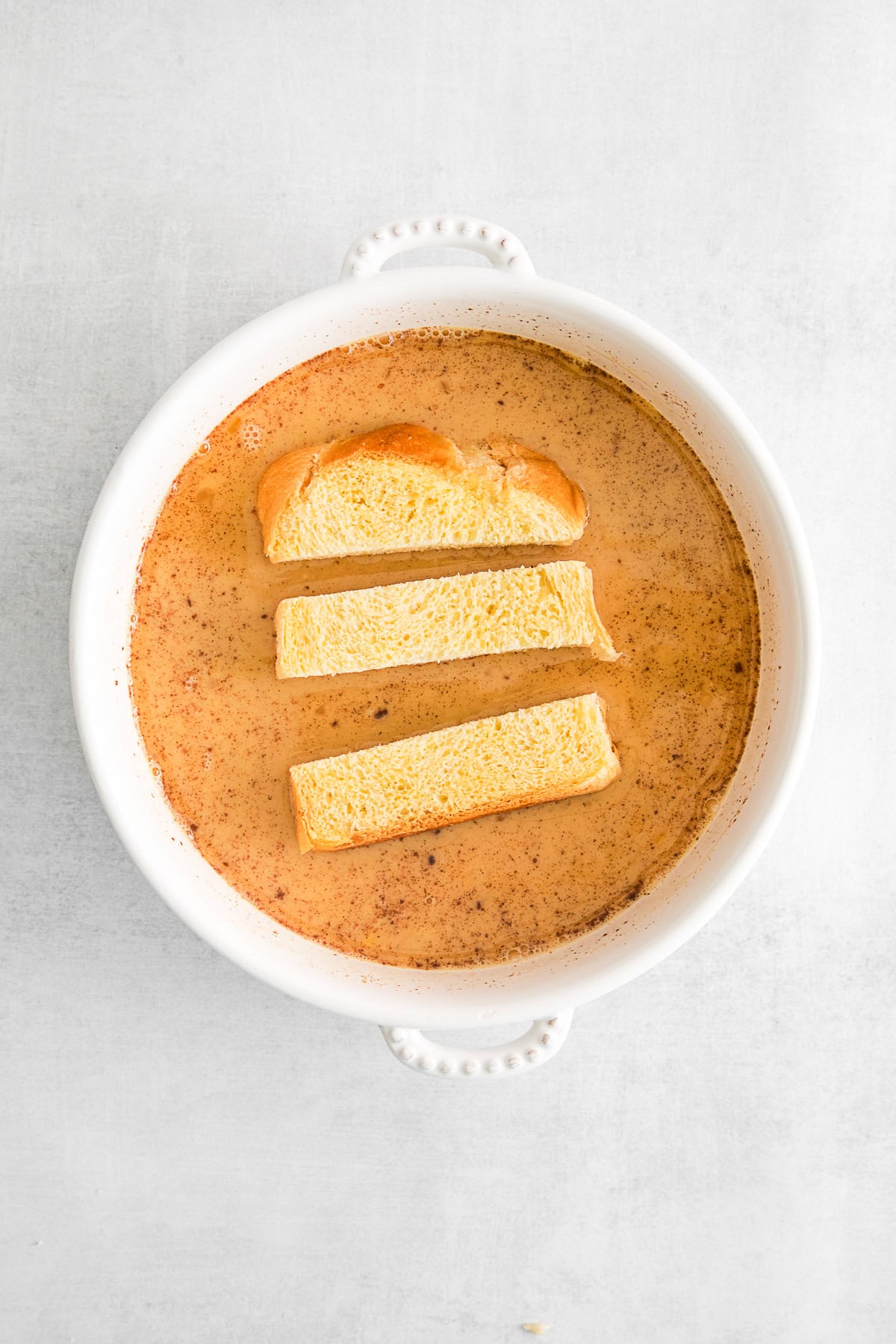 Brioche bread sticks sitting in maple custard.