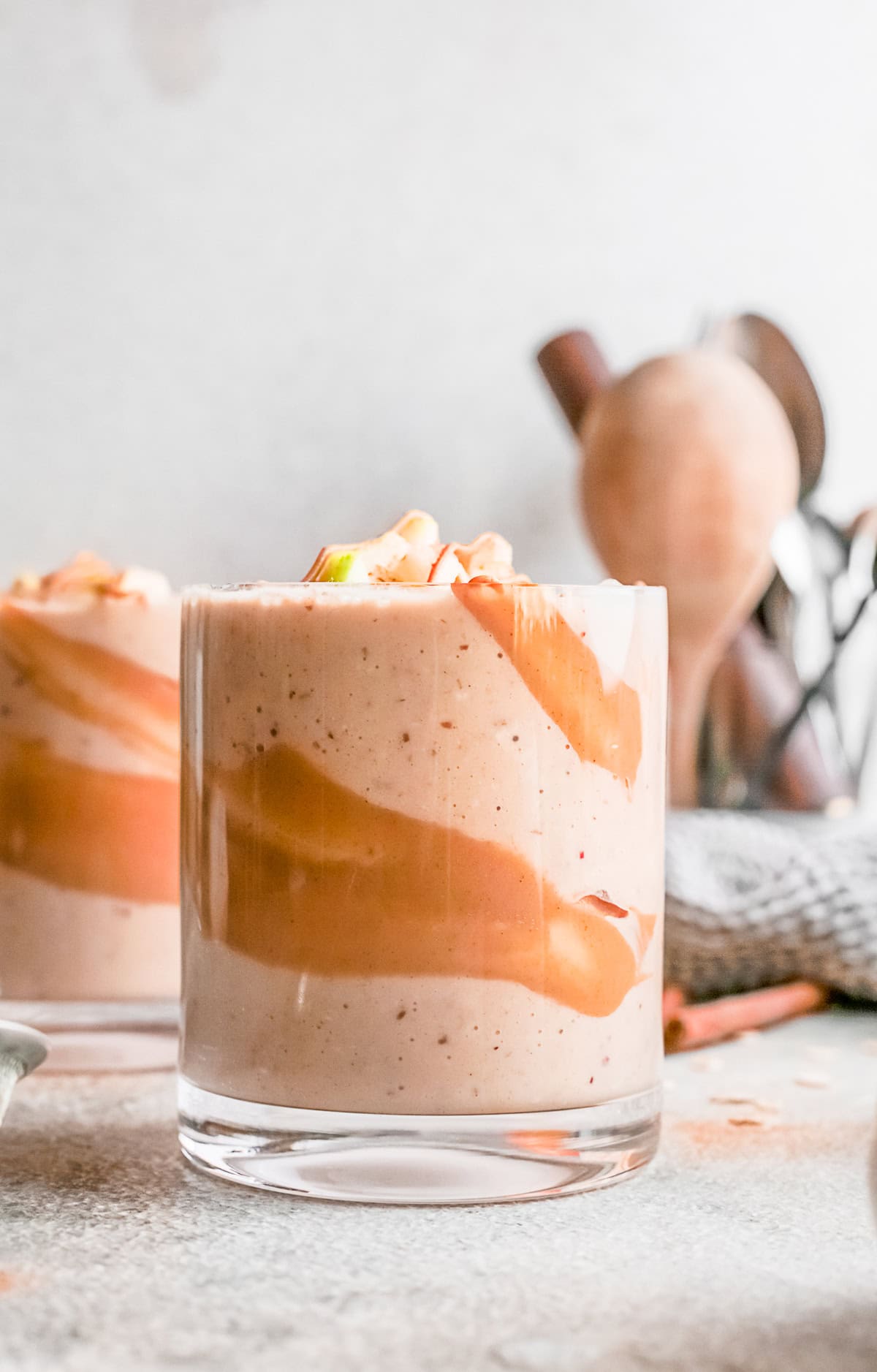 Apple pie smoothie in a glass with apples on top.