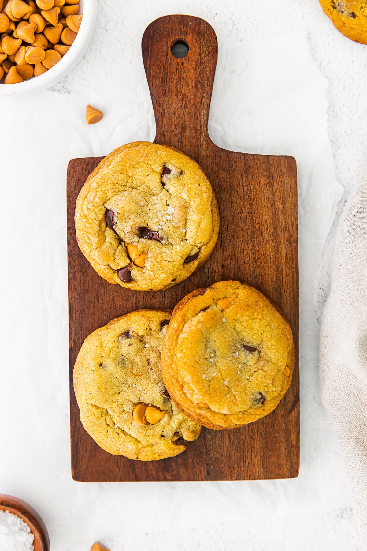 Butterscotch Chocolate Chip Cookies sitting on a wooden cutting board. 