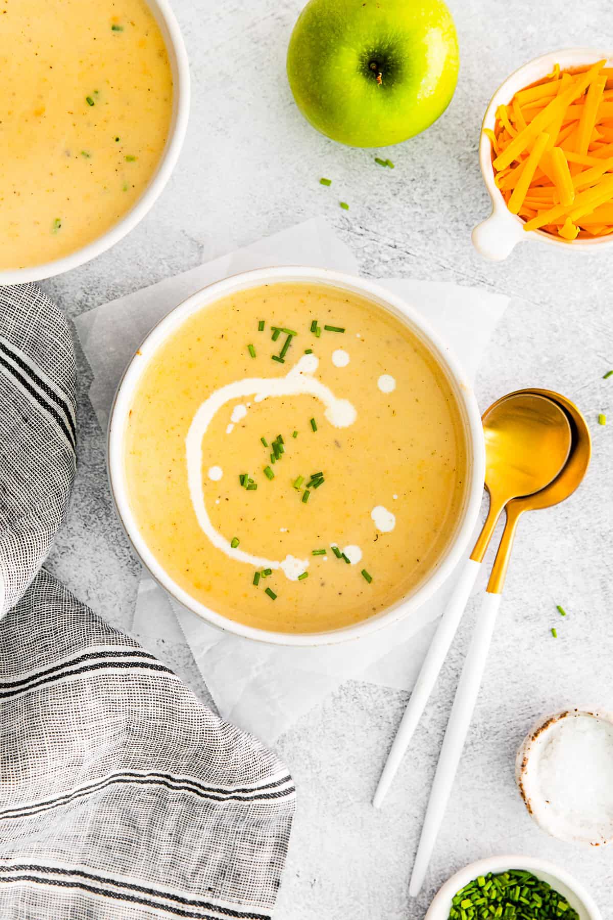 Apple Cheddar Soup in a white bowl with a drizzle of sour cream on top. 