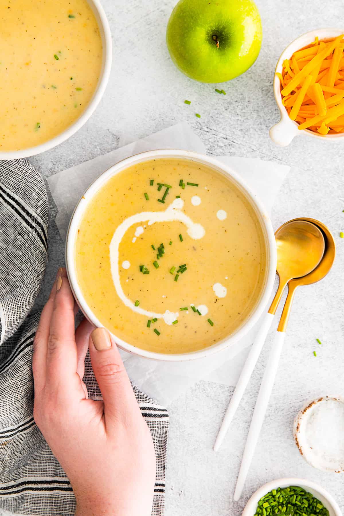 Apple Cheddar Soup with a hand holding the bowl. 
