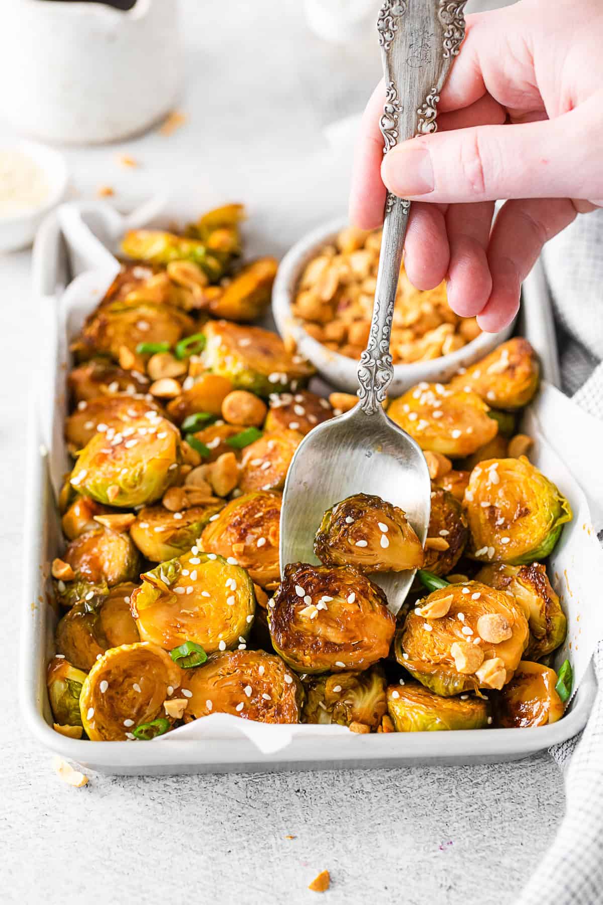 A spoon taking a serving of Kung Pao Brussels Sprouts from a pan. 