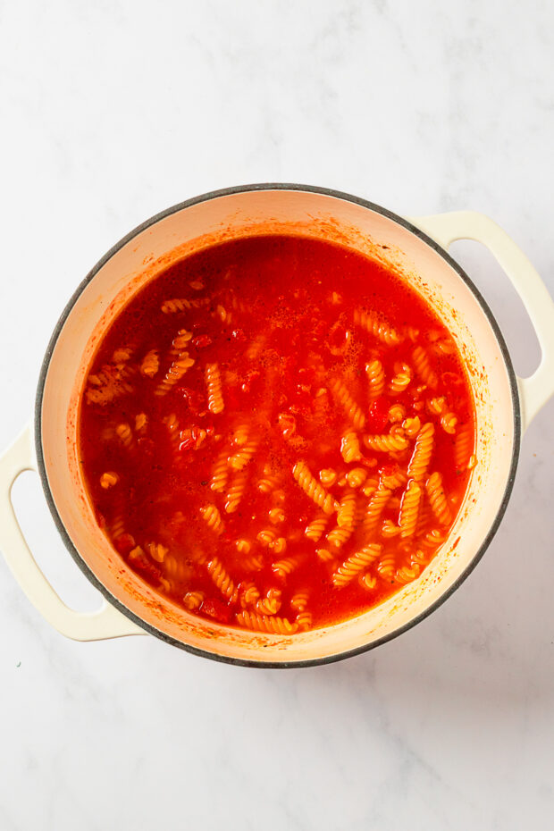 Pasta cooking in a pot with tomatoes. 