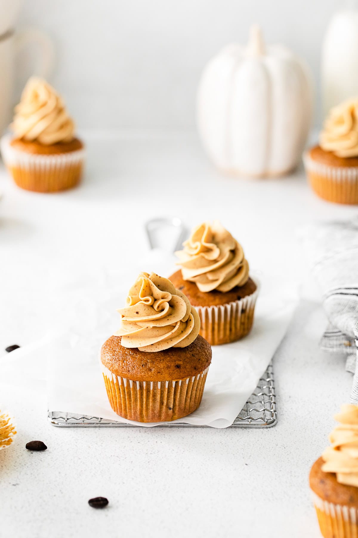 Pumpkin Spice Latte Cupcakes in a cupcakes wrapper sitting on parchment paper. 