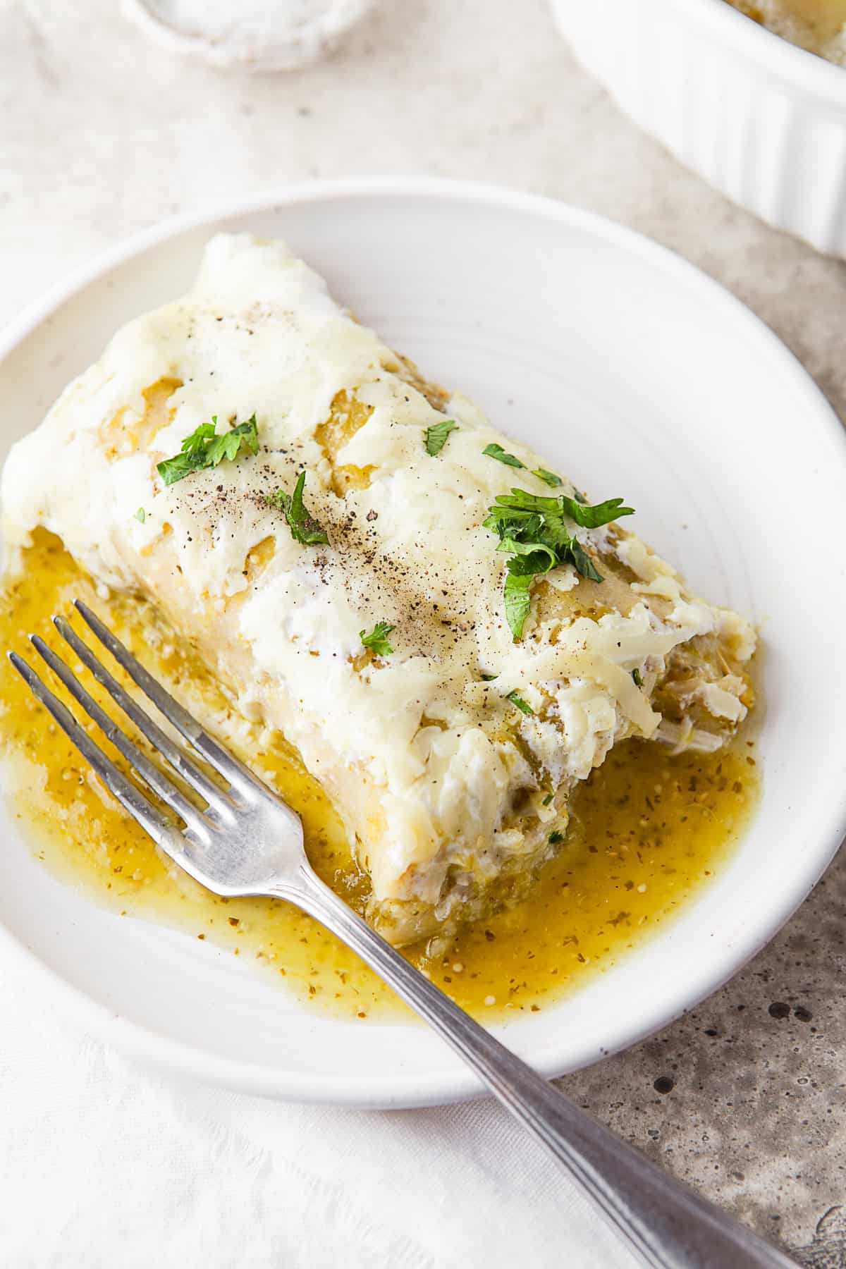 Salsa Verde Chicken Enchiladas on a plate with a fork. 