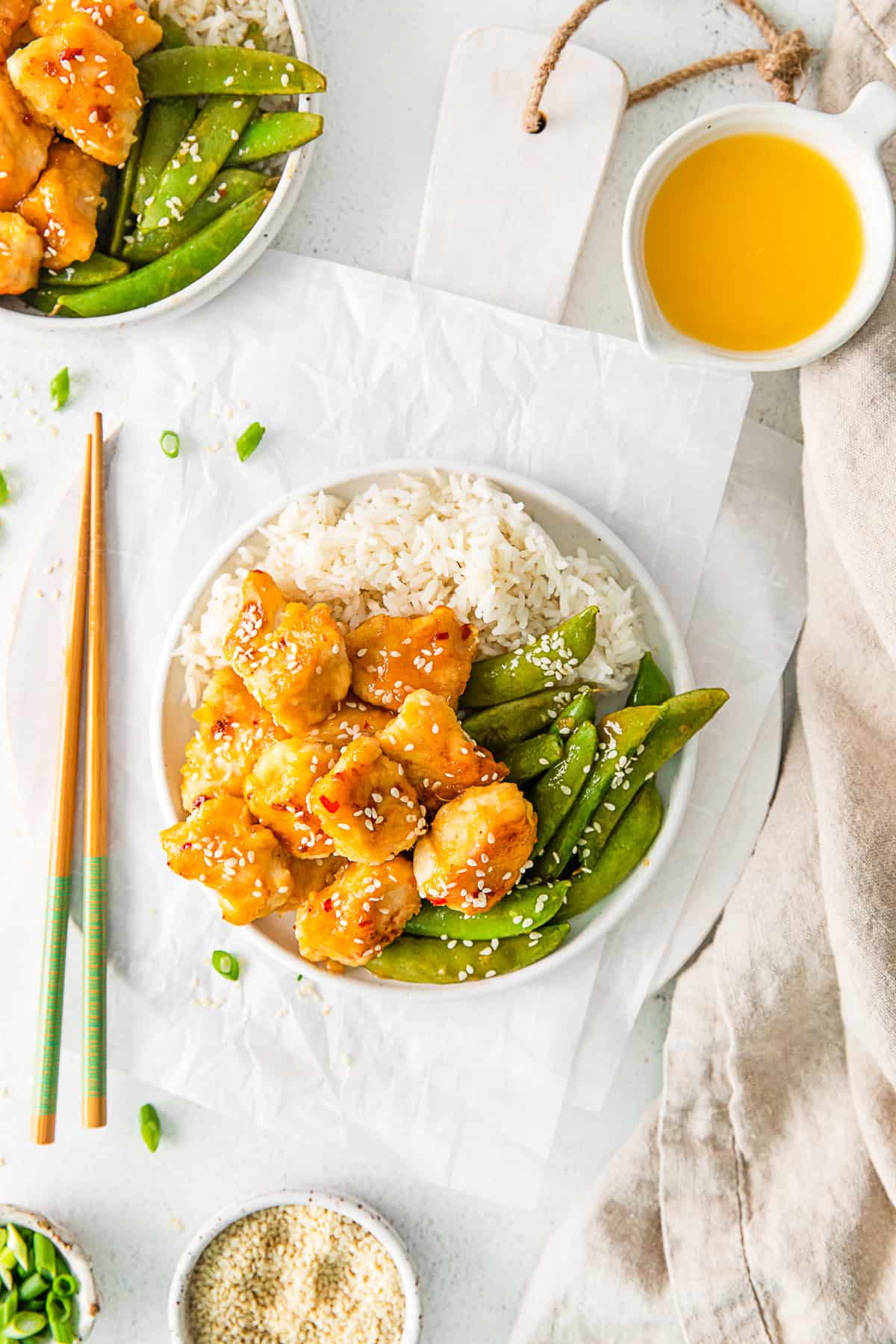 Sheet Pan Orange Chicken served with chop sticks and sesame seeds. 