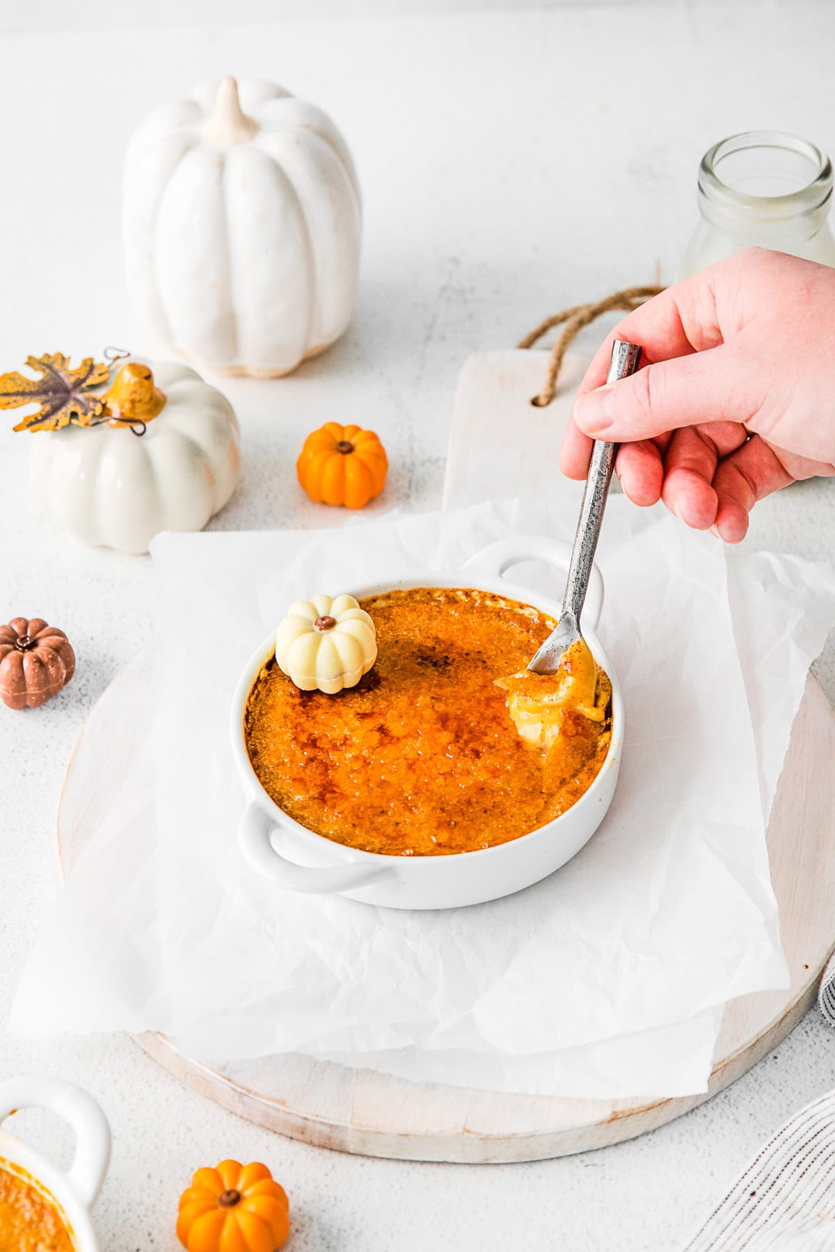 A hand holding a spoon taking a bite of Pumpkin Creme Brulee. 