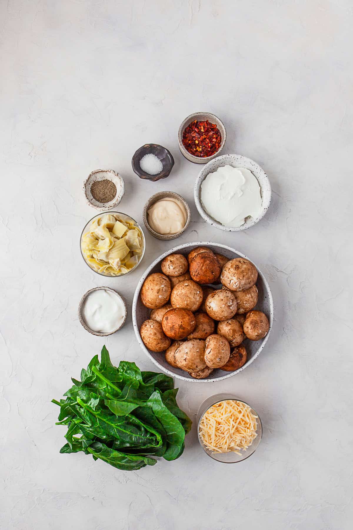 Ingredients to make Spinach Artichoke Stuffed Mushrooms on a table.