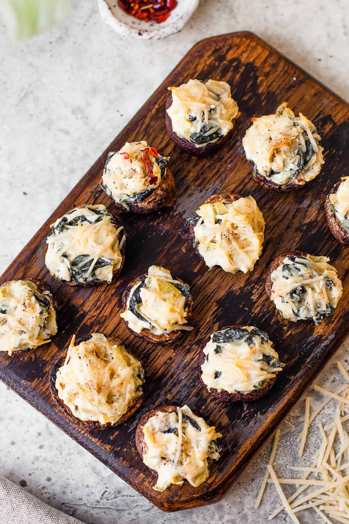 Spinach Artichoke Stuffed Mushrooms topped with cheese.
