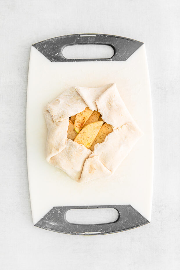 Uncooked apple galette on a cutting board. 