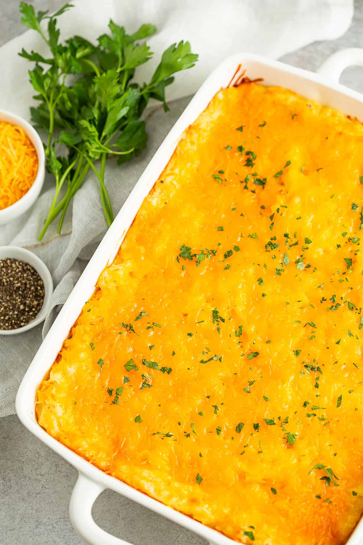 Cheesy Potatoes (Funeral Potatoes) topped with cheese in a casserole dish. 