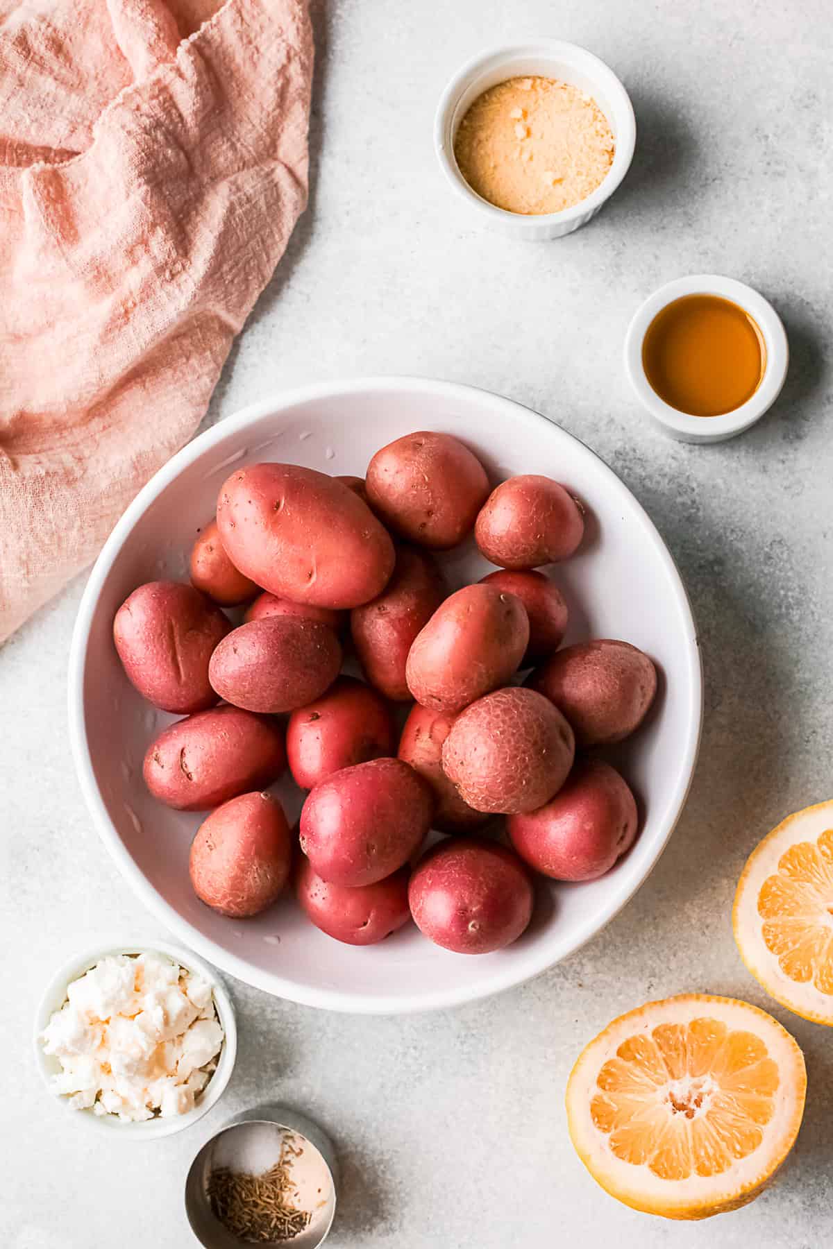 Red potatoes, olive oil, lemon, and spices on a table. 