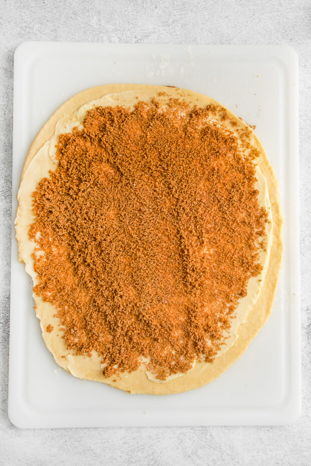 Cinnamon roll dough sprinkled with butter and cinnamon sugar.