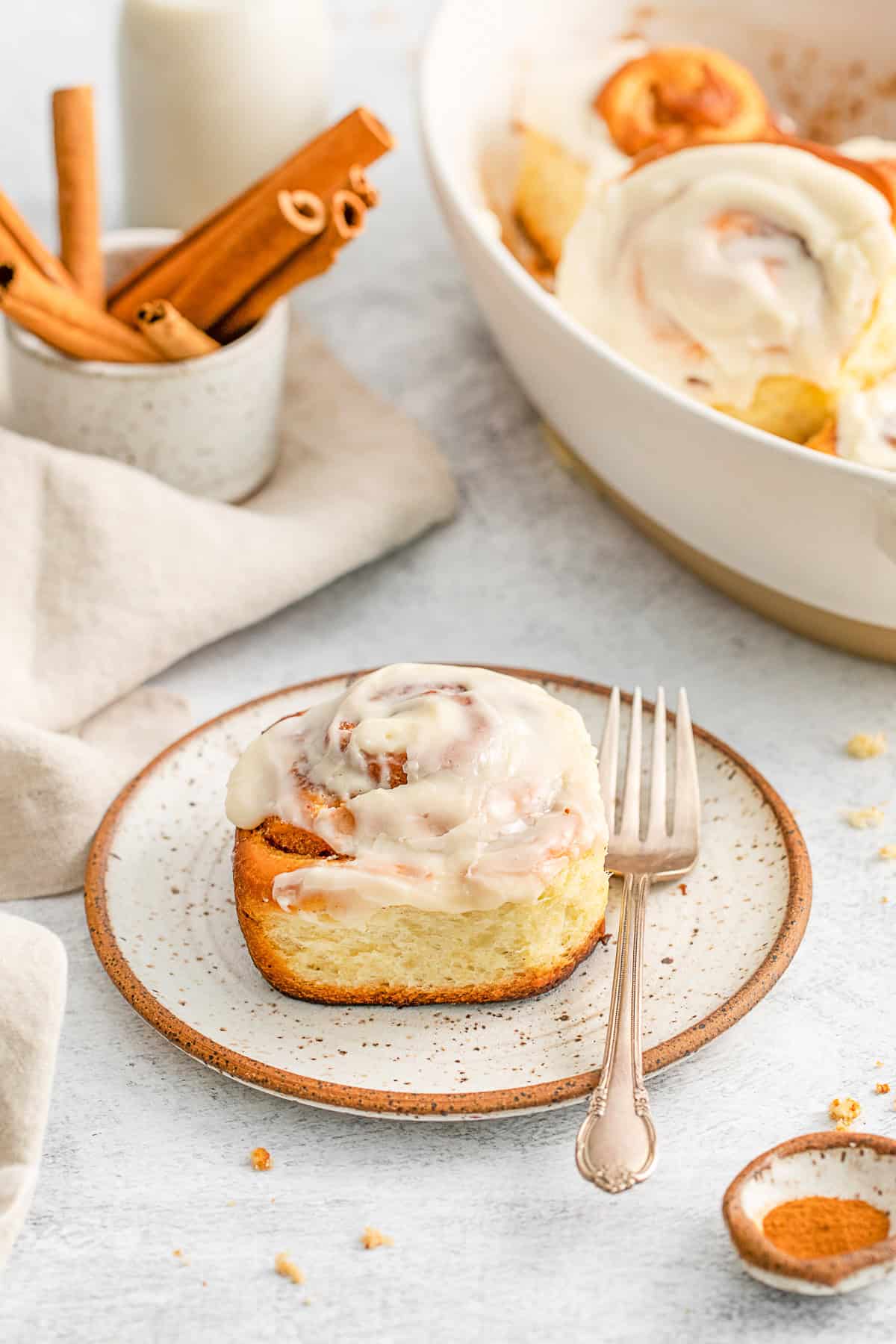 Cinnamon roll on a plate with a fork.