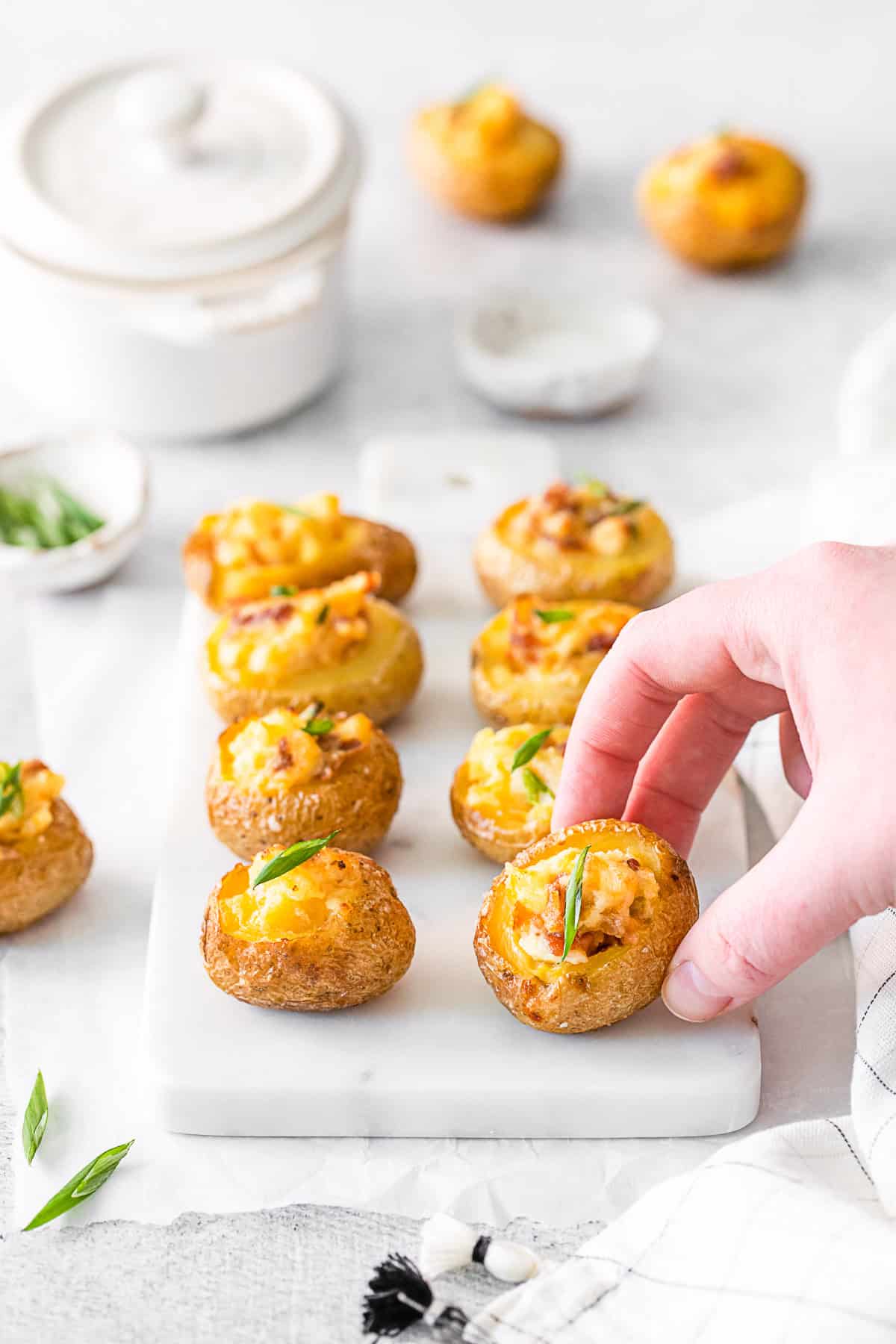 A hand picking up a Mini Loaded Baked Potato. 