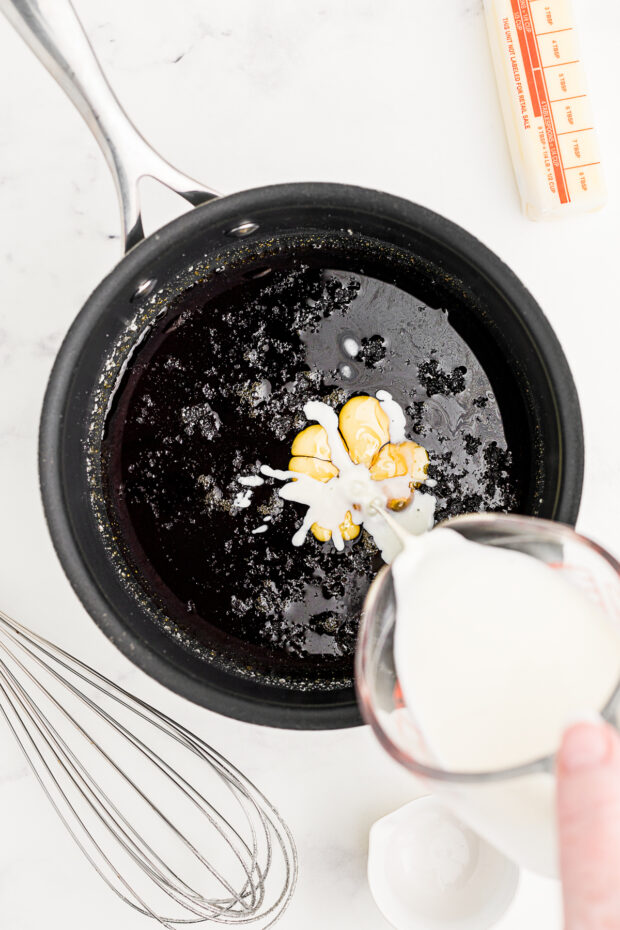 Heavy cream being poured into melted sugar.