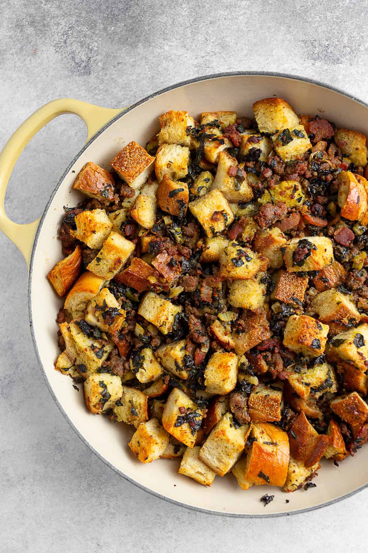 Sourdough Kale Bacon Sausage Stuffing in a yellow skillet. 