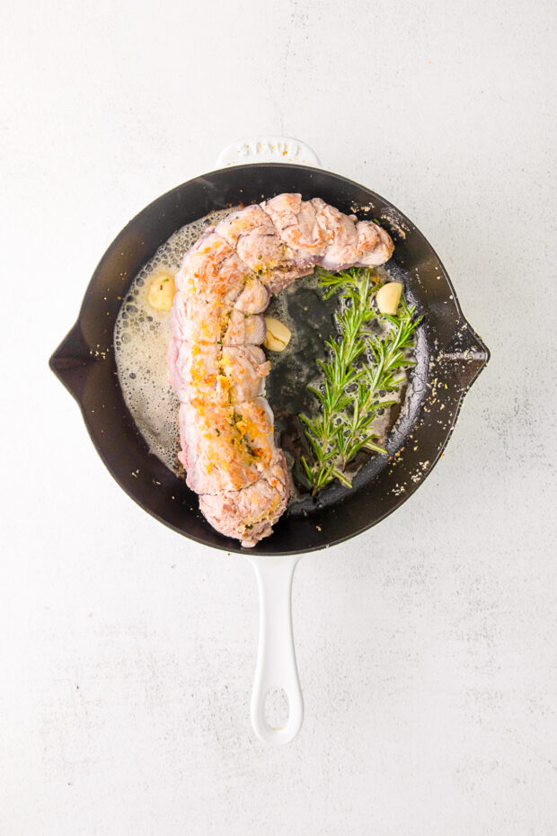 Stuffed Pork Tenderloin cooking in a skillet.