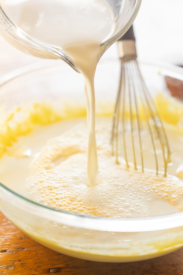 Pouring milk into egg yolks and sugar.