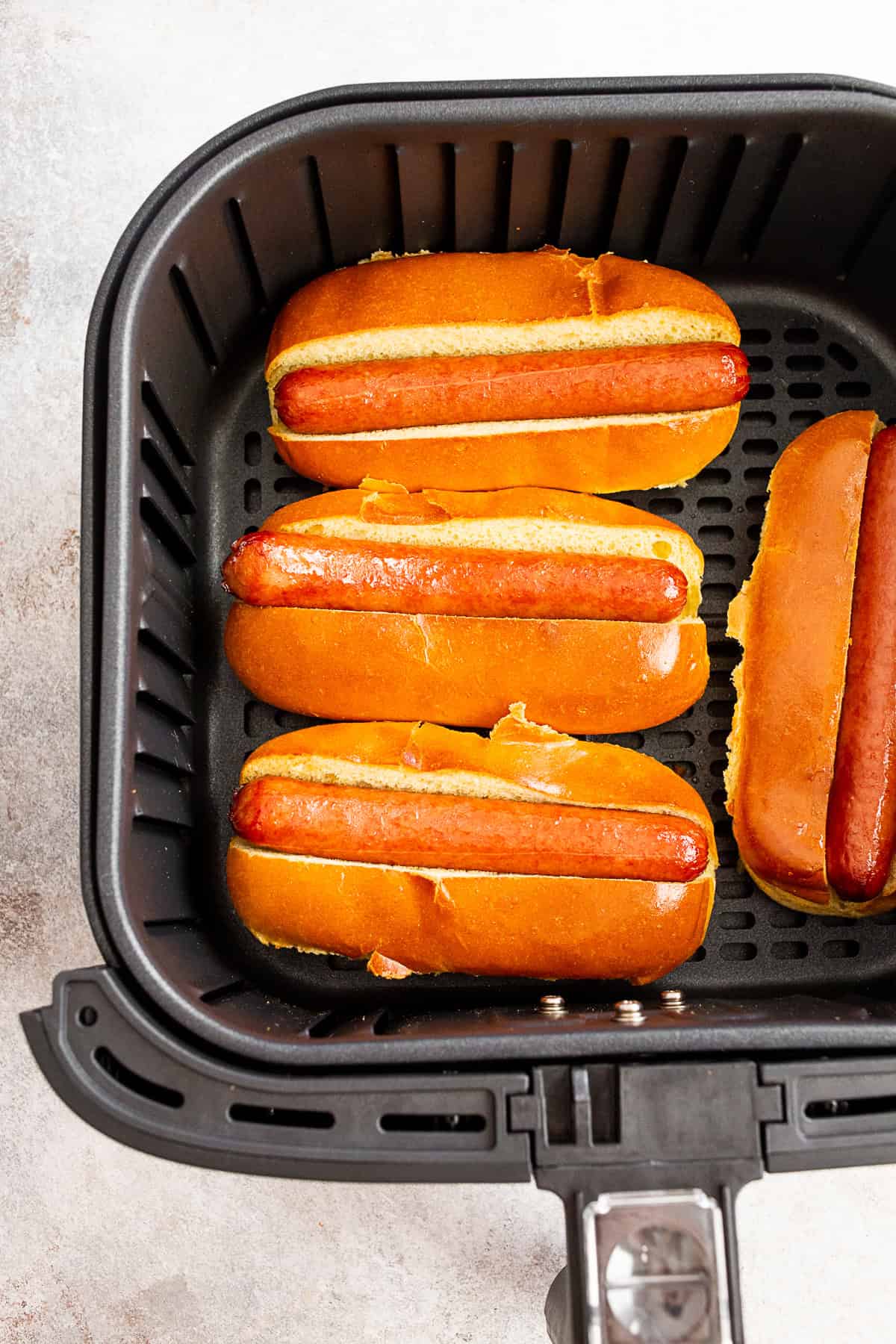 cooked air fryer hot dogs in an air fryer basket.
