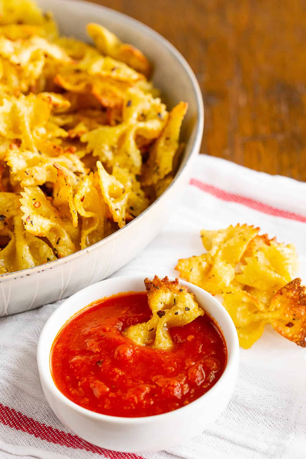 air fryer pasta chips in a bowl with tomato sauce for dipping.