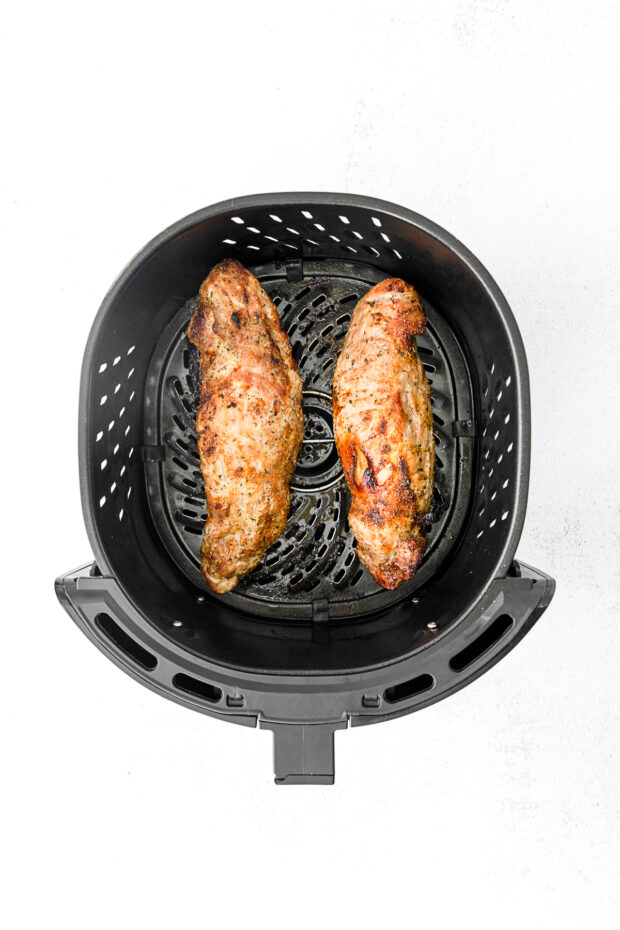 Cooked pork tenderloin in an air fryer basket. 