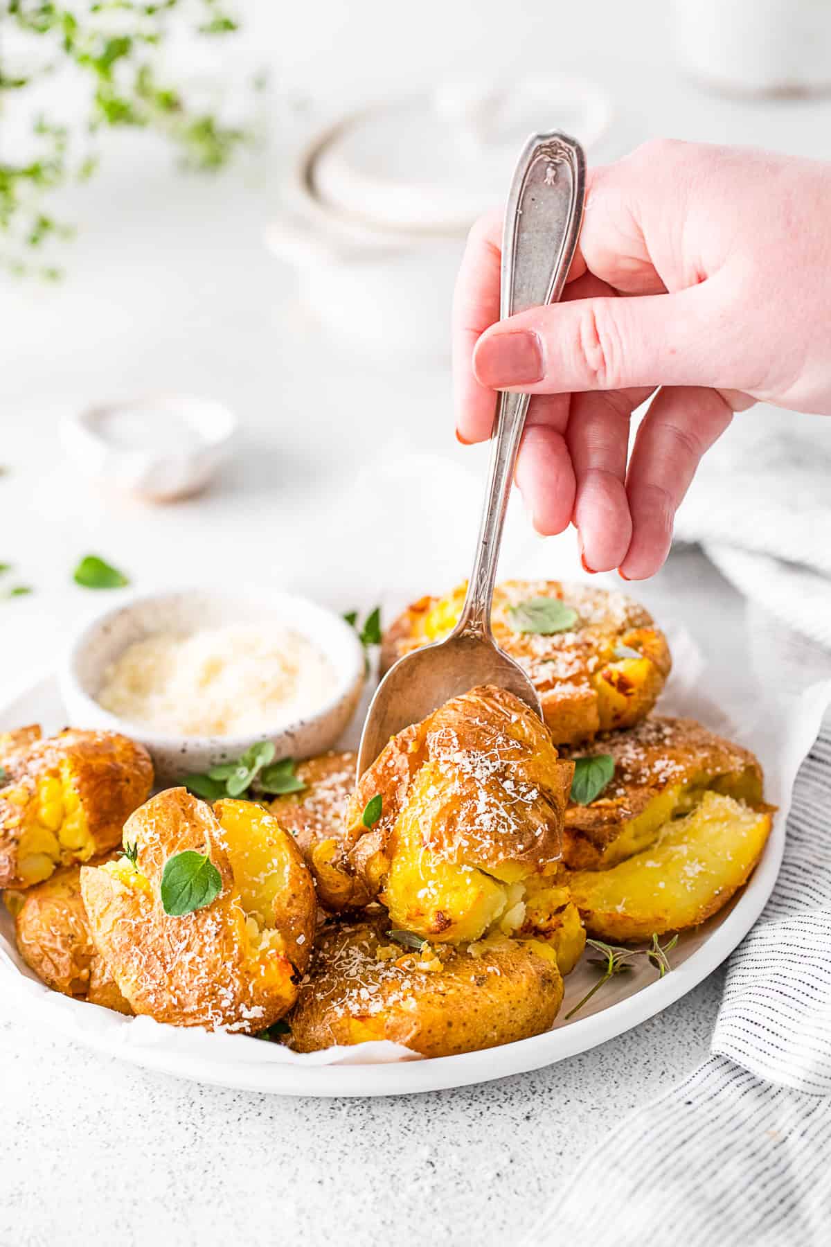 A spoon picking up a smashed potato. 