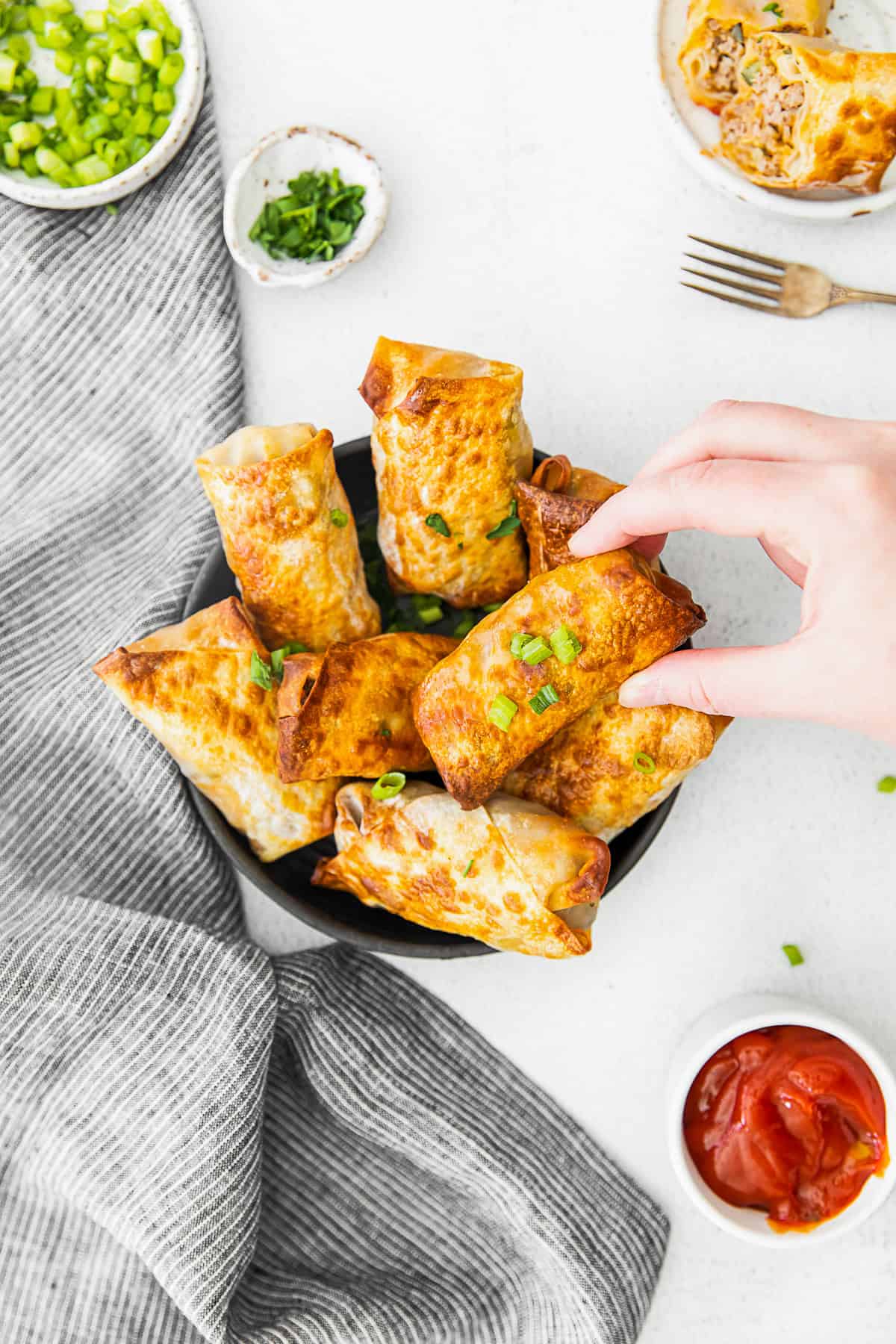A hand grabbing a cheeseburger egg roll.