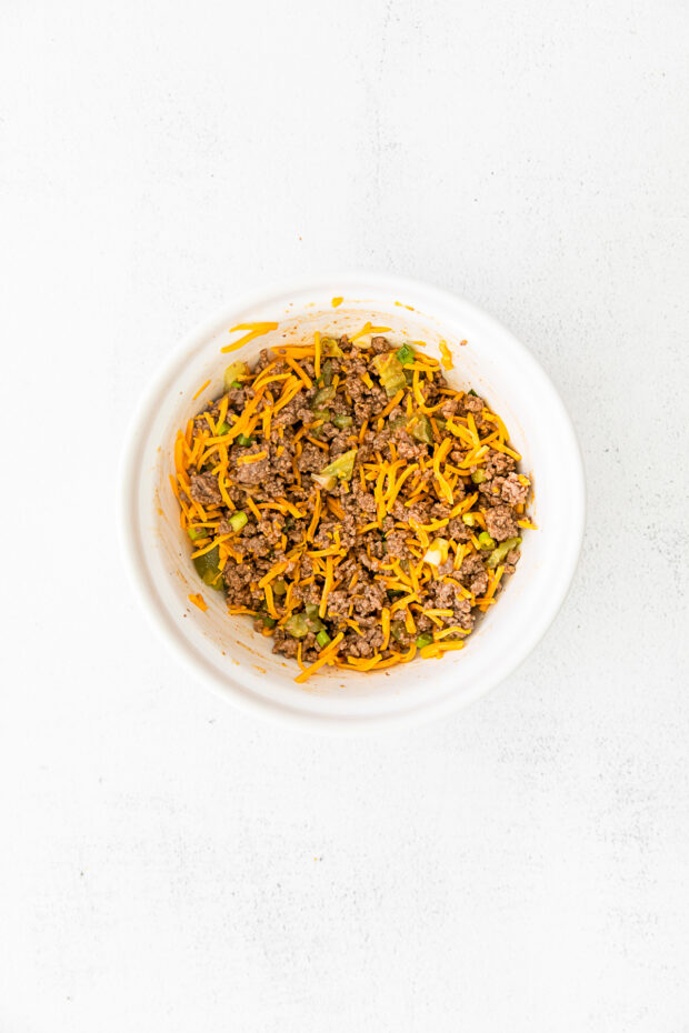 A bowl mixed with cheeseburger egg roll filling.