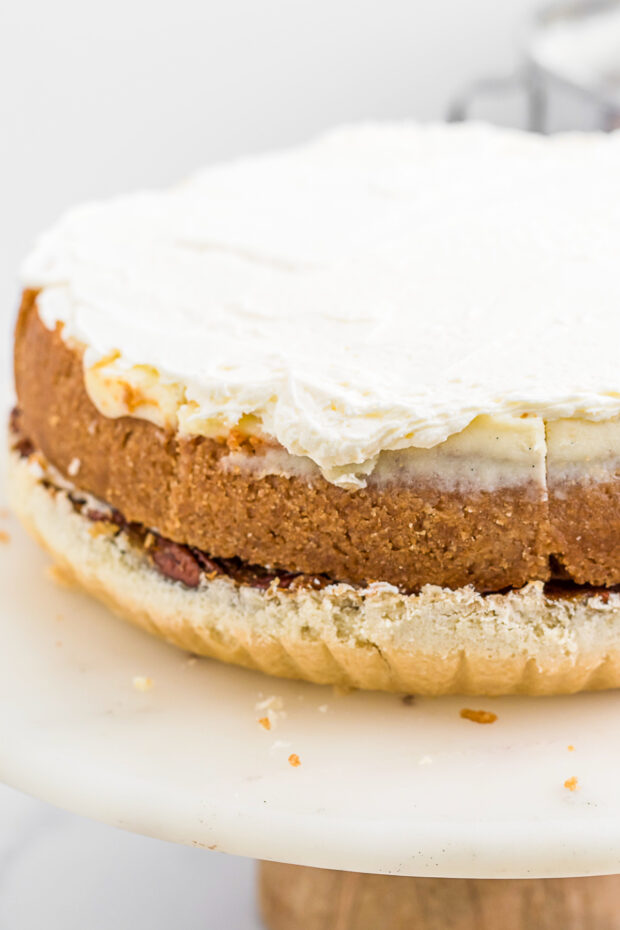 A cheesecake sitting on a pecan pie. 